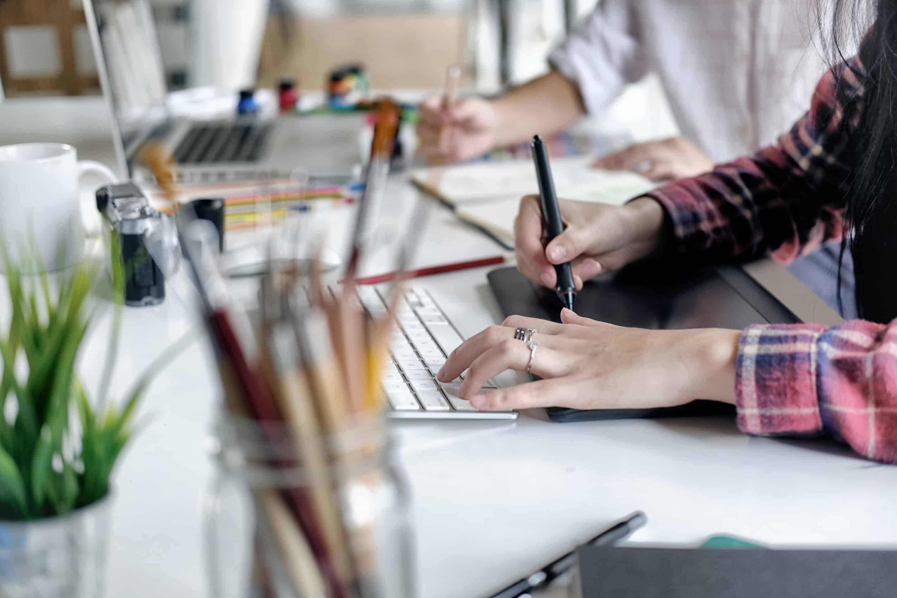 young female designer using graphics tablet while working with computer at studio or office.